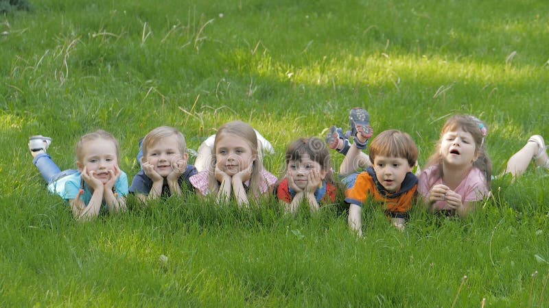 Un gruppo di bambini felici sdraiati sull'erba verde all'aperto nel parco di primavera