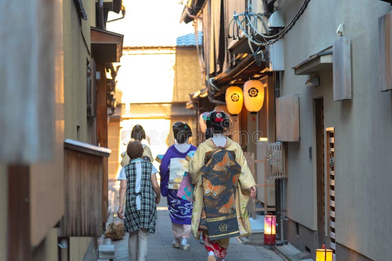 Un gruppo di geisha e di maiko che portano il kimono tradizionale del vestito che cammina sulla via fotografia stock libera da diritti Un gruppo di geisha e di maiko che portano il kimono tradizionale del vestito che cammina sulla via fotografia stock libera da diritti