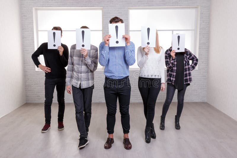 Un gruppo di persone sta con una freccia e copre i loro fronti di strati con i punti esclamativi fotografia stock Un gruppo di persone sta con una freccia e copre i loro fronti di strati con i punti esclamativi fotografia stock