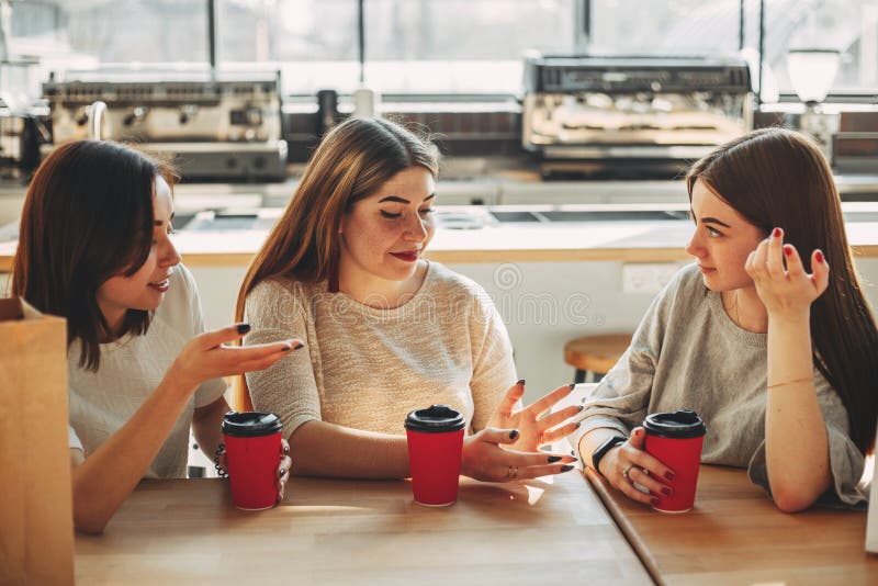 Un gruppo di tre amici divertendosi un caffè insieme Giovani donne immagini stock Un gruppo di tre amici divertendosi un caffè insieme Giovani donne immagini stock