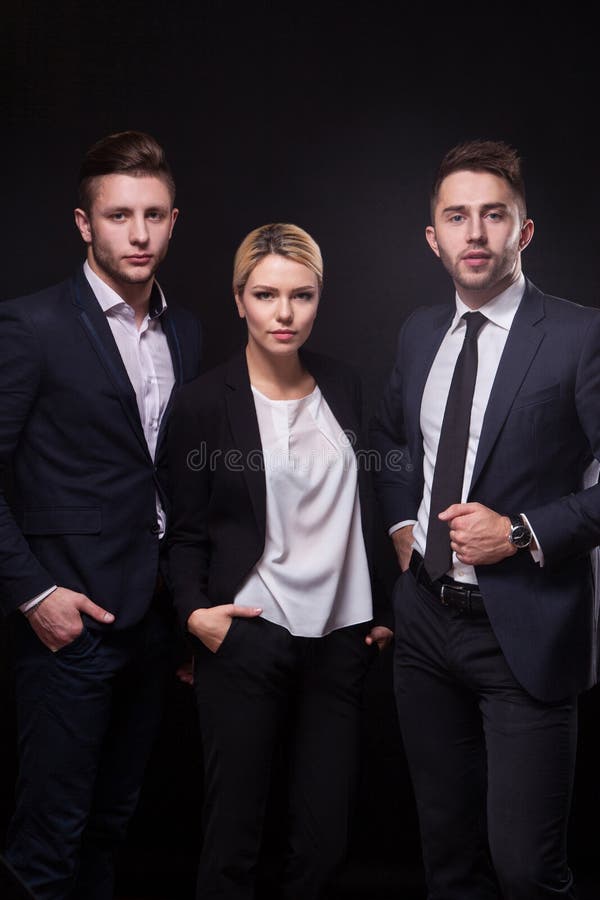 Un gruppo di tre riusciti giovani avvocati alla moda su un backgr nero fotografia stock Un gruppo di tre riusciti giovani avvocati alla moda su un backgr nero fotografia stock