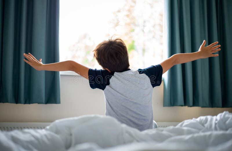Un heureux frais de garçon se réveille le matin. Image floue douce de mise au point d'un garçon mignon se réveillant allongeant le corps au lit après s'être réveillé le matin, soleil dans l'ensemble de la fenêtre le matin