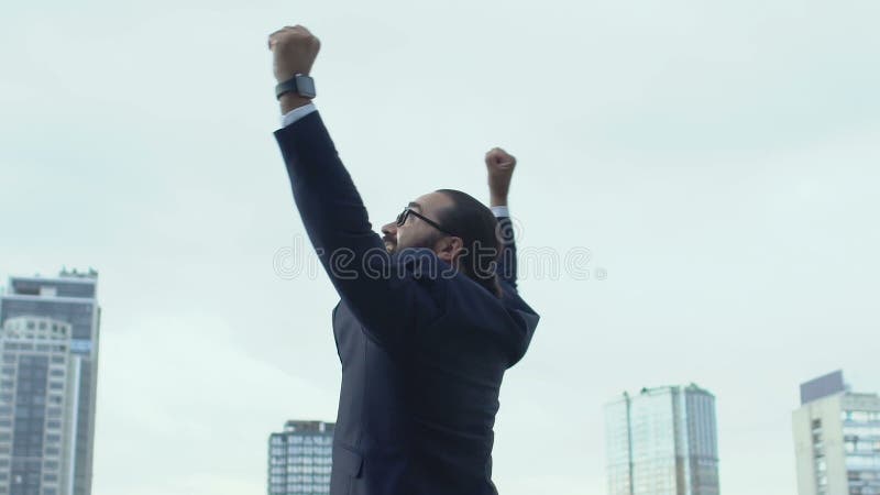 Un hombre alegre en traje de negocios levantando las manos celebrando el éxito, gesto del ganador