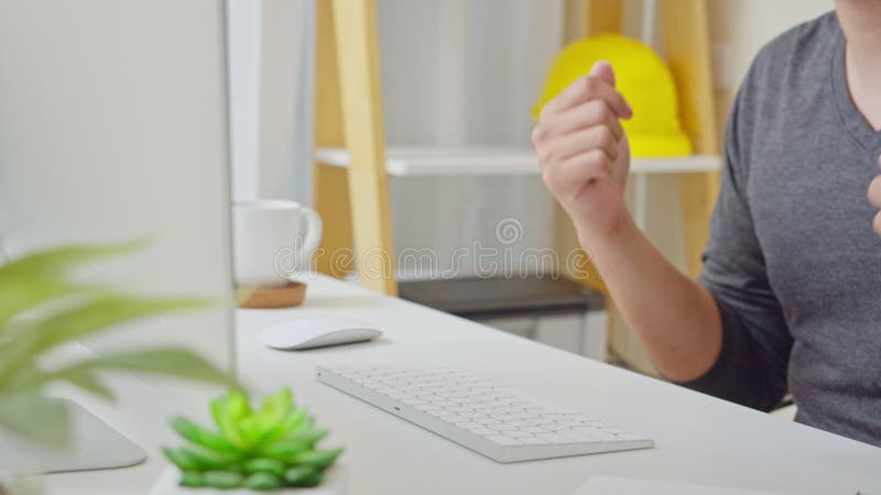 Un hombre asiático trabaja en casa disfrutando de la música mientras usa una computadora de escritorio, tecleo a mano de cerca Fe