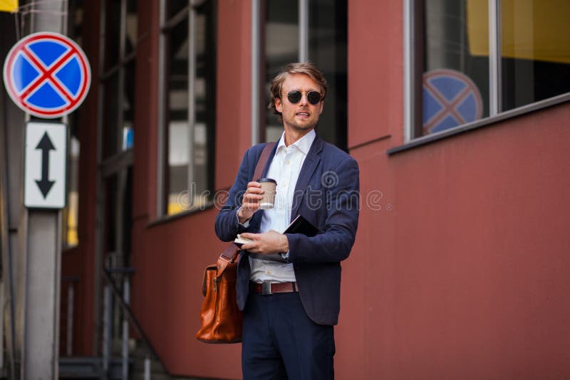 Hombre Atractivo Con Ropa Formal Y Lentes De Sol Disfruta De Su Café Al Aire Libre Cerca De La Oficina Imagen de archivo - Imagen tenencia, caminar: 164067767