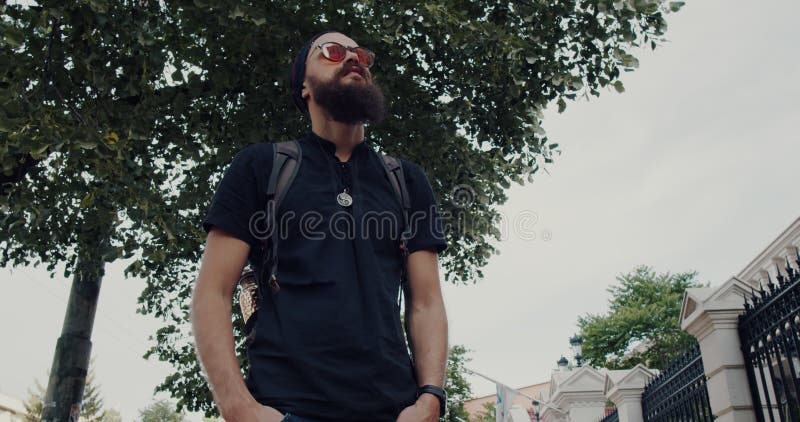 Un hombre barbudo reflexiona sobre la naturaleza y la vida urbana en este video almacen de metraje de vídeo
