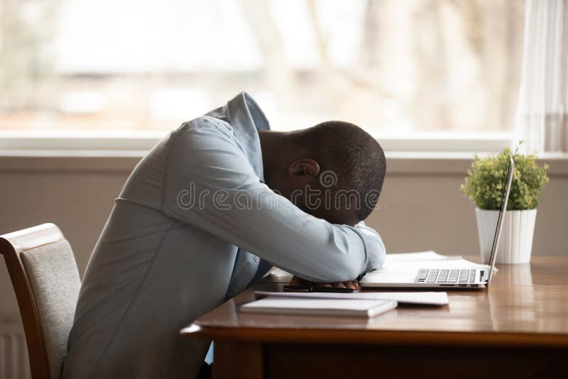 Un hombre birracial exhausto se queda dormido trabajando en una laptop