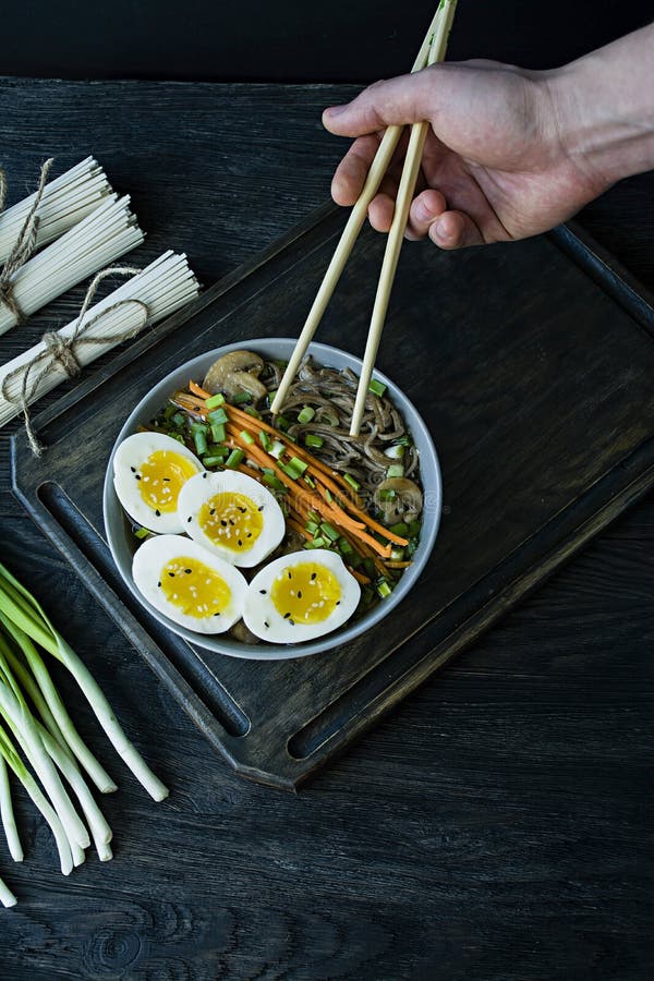 Un hombre come los tallarines del soba del alforf?n con la salsa y los acompa?amientos en caldo Comida japonesa Cocina asi?tica F imagen de archivo Un hombre come los tallarines del soba del alforf?n con la salsa y los acompa?amientos en caldo Comida japonesa Cocina asi?tica F imagen de archivo