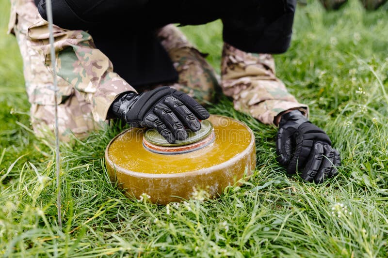 Un hombre con uniforme militar y chaleco antibalas trabaja en el bosque  para desminar el territorio