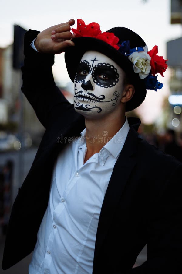 Un Hombre Con Una Cara Pintada De Un Esqueleto, Zombi Muerto, En La Ciudad  Durante El Día Día De Todas Las Almas, Día De Los Muer Imagen de archivo -  Imagen de