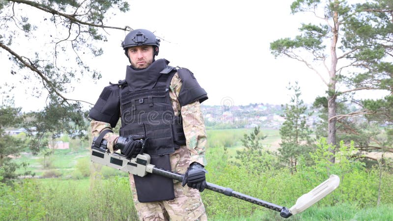 Un Hombre Con Uniforme Militar Y Chaleco Antibalas Trabaja En El Bosque Con  Un Detector De Metales. Metrajes - Vídeo de exterior, contento: 279898460