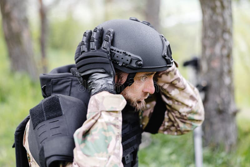 Un Hombre Con Uniforme Militar Y Un Chaleco Antibalas Trabaja En El Bosque  Para Desminar El Territorio. Un Hombre Se Pone Un Casco Imagen de archivo -  Imagen de armado, profundamente: 277401063