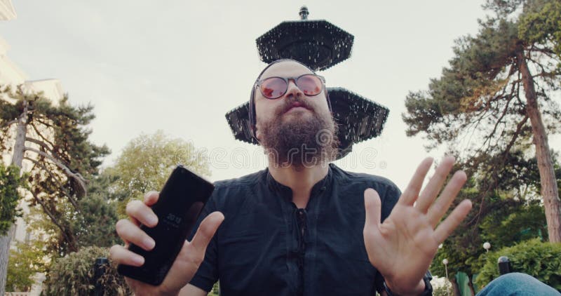 Un hombre de diseño con barba disfruta del ocio al aire libre combinando tecnología y naturaleza almacen de video