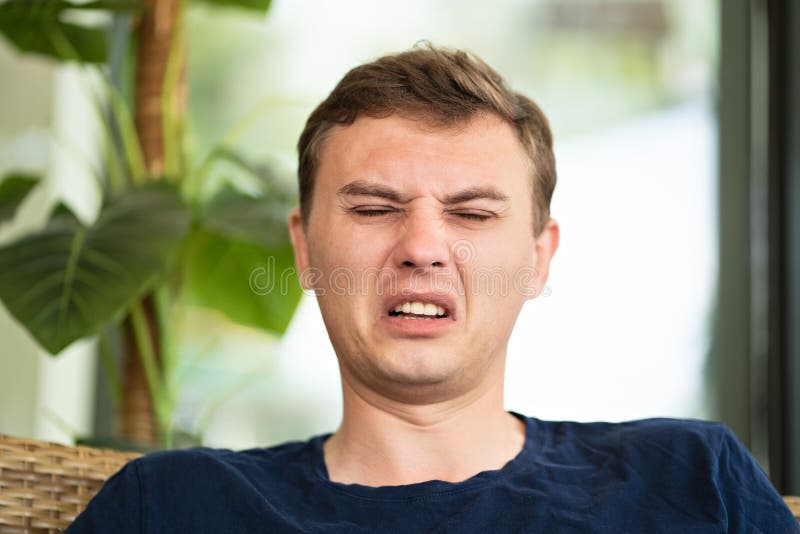 Un hombre de mediana edad con un rostro disgustado estornuda.