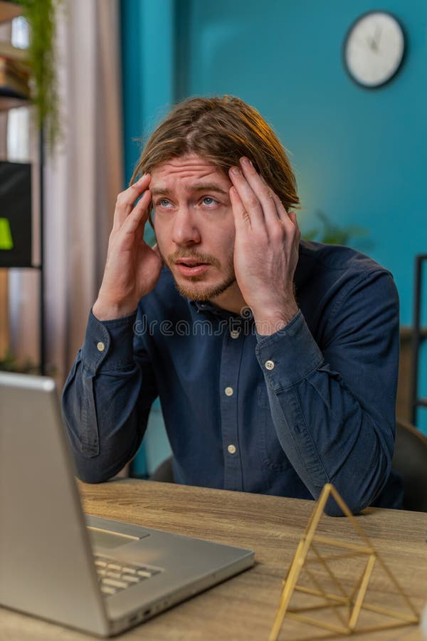 Un hombre de negocios cansado y enfermo que sufre de dolor de cabeza tensión y migraña estrés en la oficina del hogar imagenes de archivo