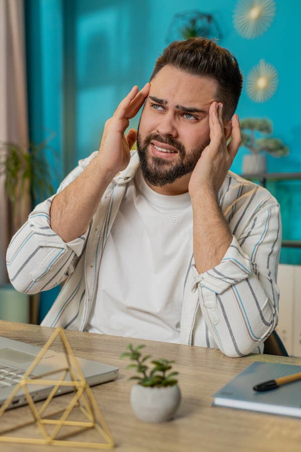 Un hombre de negocios cansado y enfermo que sufre de dolor de cabeza tensión y migraña estrés en la oficina del hogar foto de archivo