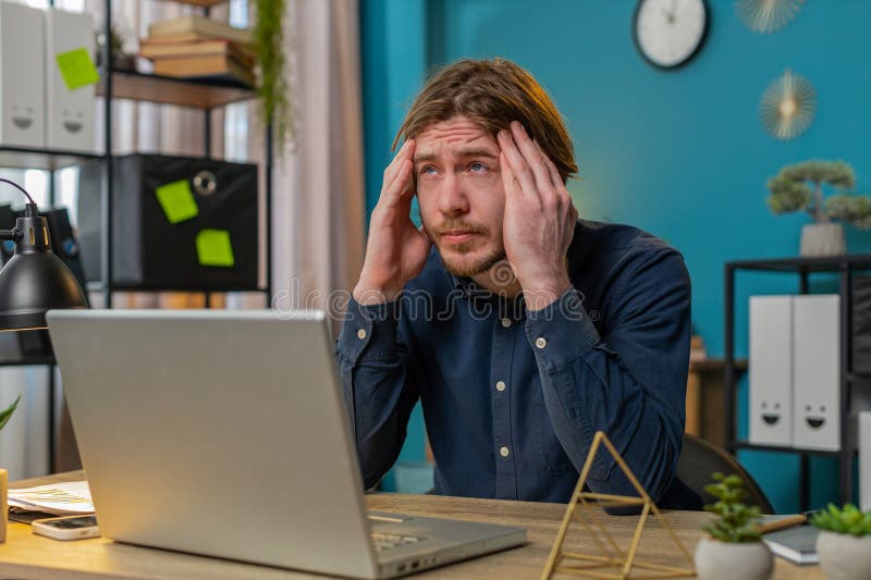 Un hombre de negocios cansado y enfermo que sufre de dolor de cabeza tensión y migraña estrés en la oficina del hogar imagen de archivo libre de regalías