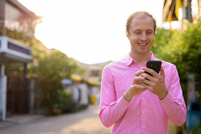 Un hombre de negocios feliz con el pelo rubio usando el teléfono al aire libre foto de archivo