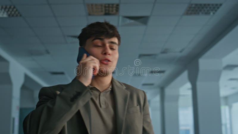 Un hombre de negocios que se ríe y llama al teléfono móvil en el claustro del moderno centro de negocios almacen de metraje de vídeo