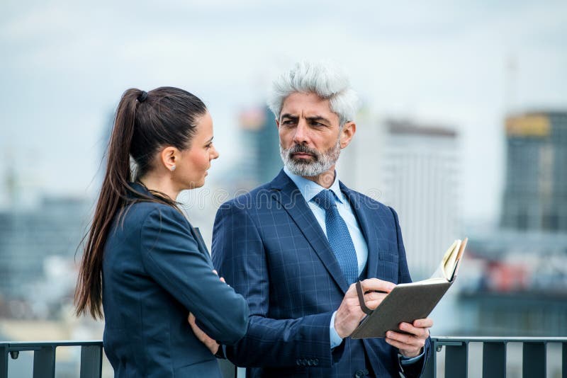 Un hombre de negocios y una mujer de negocios con un diario en la terraza, trabajando imagen de archivo libre de regalías Un hombre de negocios y una mujer de negocios con un diario en la terraza, trabajando imagen de archivo libre de regalías