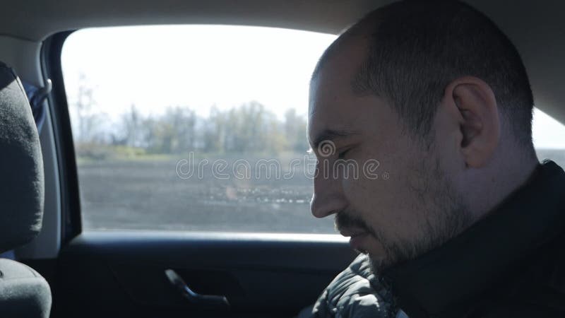 Un hombre duerme dentro de un auto en movimiento durante un largo viaje. retrato de un pasajero cansado que viaja en coche. viaje metrajes