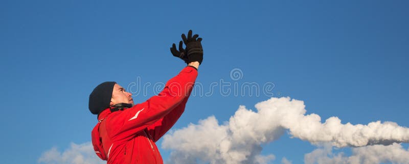 Un hombre en la chaqueta roja que mira el cielo con las manos que soporta Fondo del cielo azul y del humo imágenes de archivo libres de regalías Un hombre en la chaqueta roja que mira el cielo con las manos que soporta Fondo del cielo azul y del humo imágenes de archivo libres de regalías
