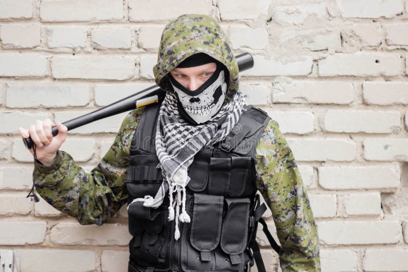 Un Hombre En Pasamontañas De Camuflaje Con Un Cráneo Y Un Chaleco Antibalas  Con Un Bate De Béisbol En Las Manos Foto de archivo - Imagen de esquina,  ataque: 207707312