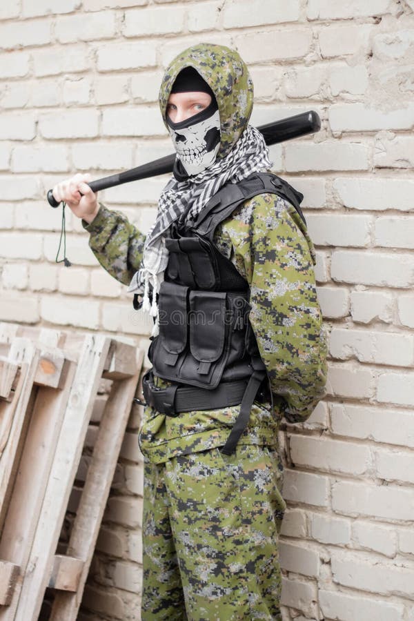 Un Hombre En Pasamontañas De Camuflaje Con Un Cráneo Y Un Chaleco Antibalas  Con Un Bate De Béisbol En Las Manos Foto de archivo - Imagen de esquina,  ataque: 207707312