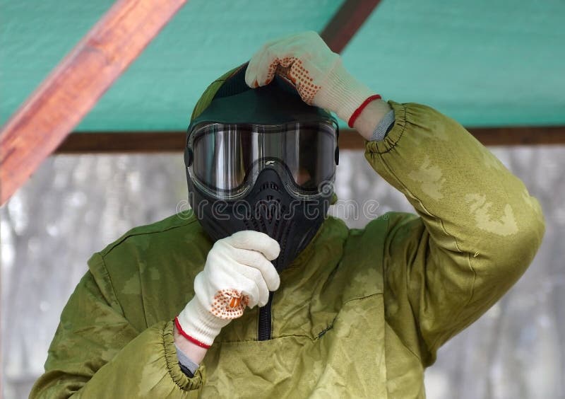 Un hombre en un uniforme especial, llevando un camuflaje para la protección al jugar Paintball imagen de archivo libre de regalías Un hombre en un uniforme especial, llevando un camuflaje para la protección al jugar Paintball imagen de archivo libre de regalías