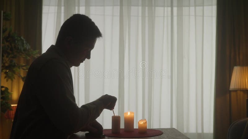 Un hombre enciende velas con fósforos y una mujer trae copas de vino. la mujer le pasa un vaso al hombre y se aferran metrajes