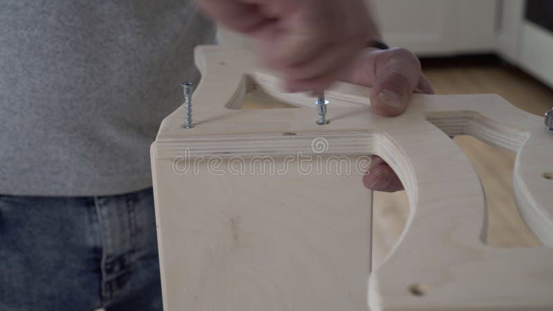 Un hombre ensambla muebles de madera con herramientas de mano cerradas