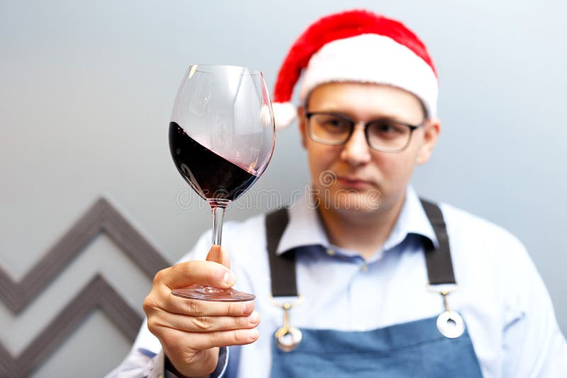 Un hombre está bebiendo el vino en un sombrero de santa foto de archivo Un hombre está bebiendo el vino en un sombrero de santa foto de archivo
