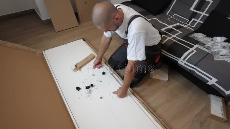 Un hombre está mirando cómo armar muebles con sus propias manos. un artesano con traje de trabajo