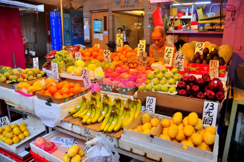 Un hombre está vendiendo en una cabina de la fruta en el og Hong Kong de la calle fotos de archivo libres de regalías Un hombre está vendiendo en una cabina de la fruta en el og Hong Kong de la calle fotos de archivo libres de regalías