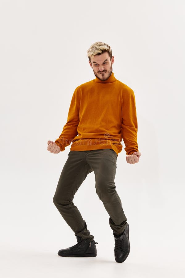 Un Hombre Feliz Con Un Suéter Naranja Y Unos Pantalones Gesticulan Con Las  Manos En Un Fondo Claro Y Doblan Las Rodillas Imagen de archivo - Imagen de  plegable, cerda: 223472661