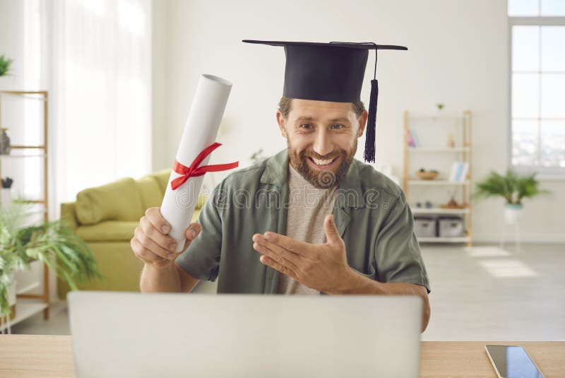 Un hombre feliz termina su carrera en línea y recibe diploma y asiste a la ceremonia de graduación a distancia foto de archivo libre de regalías