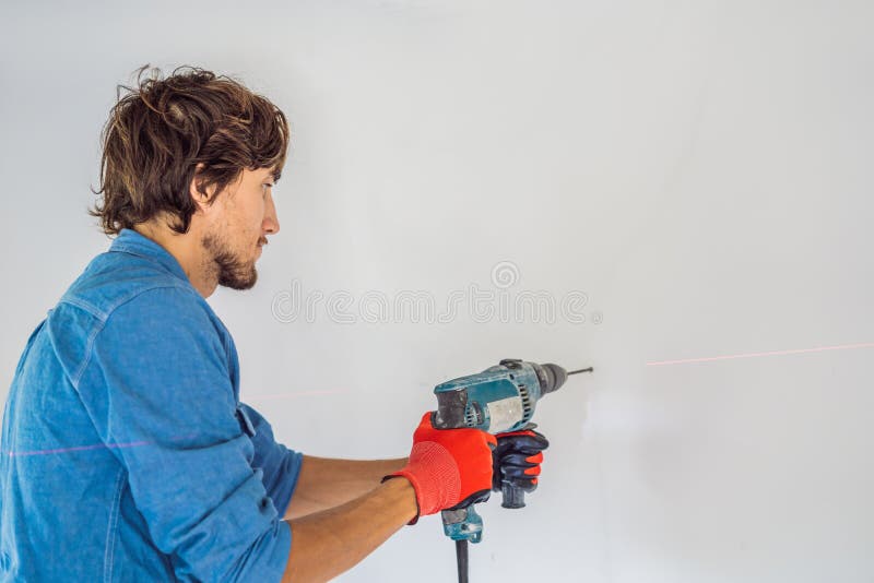 Un hombre hace un agujero en la pared con un taladro fotos de archivo libres de regalías Un hombre hace un agujero en la pared con un taladro fotos de archivo libres de regalías
