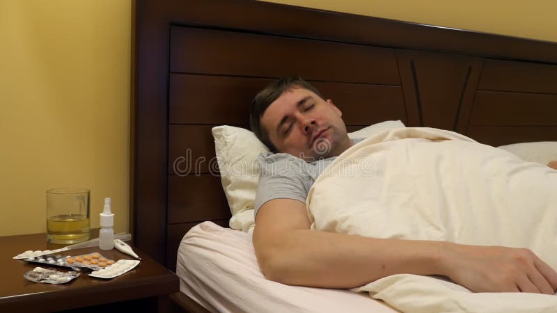 Un hombre joven enfermo en una cama metrajes