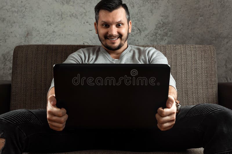 Un hombre mira un v?deo adulto en un ordenador port?til mientras que se sienta en el sof? El concepto de pornograf?a, las necesid imagenes de archivo Un hombre mira un v?deo adulto en un ordenador port?til mientras que se sienta en el sof? El concepto de pornograf?a, las necesid imagenes de archivo