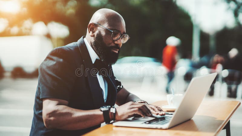 Un hombre negro con un ordenador port?til en un caf? imagen de archivo Un hombre negro con un ordenador port?til en un caf? imagen de archivo