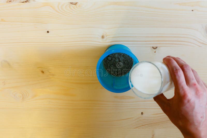 Un hombre vierte la leche de un vidrio en una coctelera azul para revolver la proteína Proteína, una forma de vida sana, la perso imagenes de archivo Un hombre vierte la leche de un vidrio en una coctelera azul para revolver la proteína Proteína, una forma de vida sana, la perso imagenes de archivo
