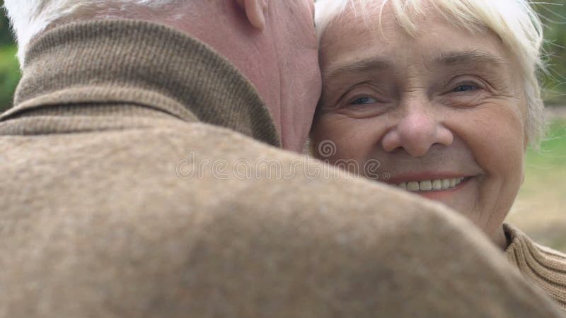 Un homme aux cheveux gris embrassant sa femme mature sur la joue, des moments romantiques, du bonheur