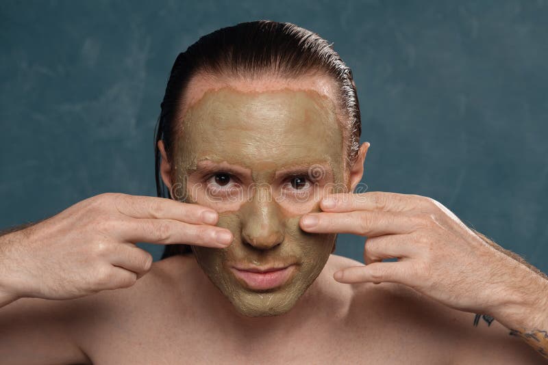 Un homme avec de longs cheveux mouillés applique un masque d'argile
