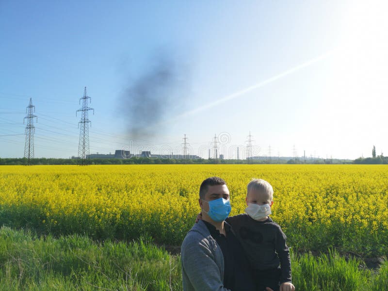 Un homme avec un enfant dans des ses mains dans les masques m?dicaux sur le fond de l'usine Le concept de la pollution environnem photographie stock libre de droits Un homme avec un enfant dans des ses mains dans les masques m?dicaux sur le fond de l'usine Le concept de la pollution environnem photographie stock libre de droits