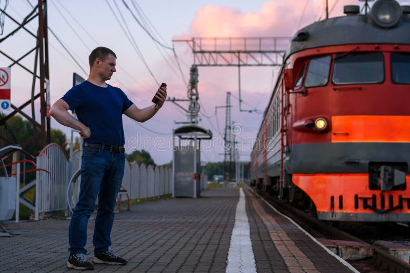 Un homme avec le vitiligo à la station de train avec un téléphone à côté du train photos libres de droits Un homme avec le vitiligo à la station de train avec un téléphone à côté du train photos libres de droits