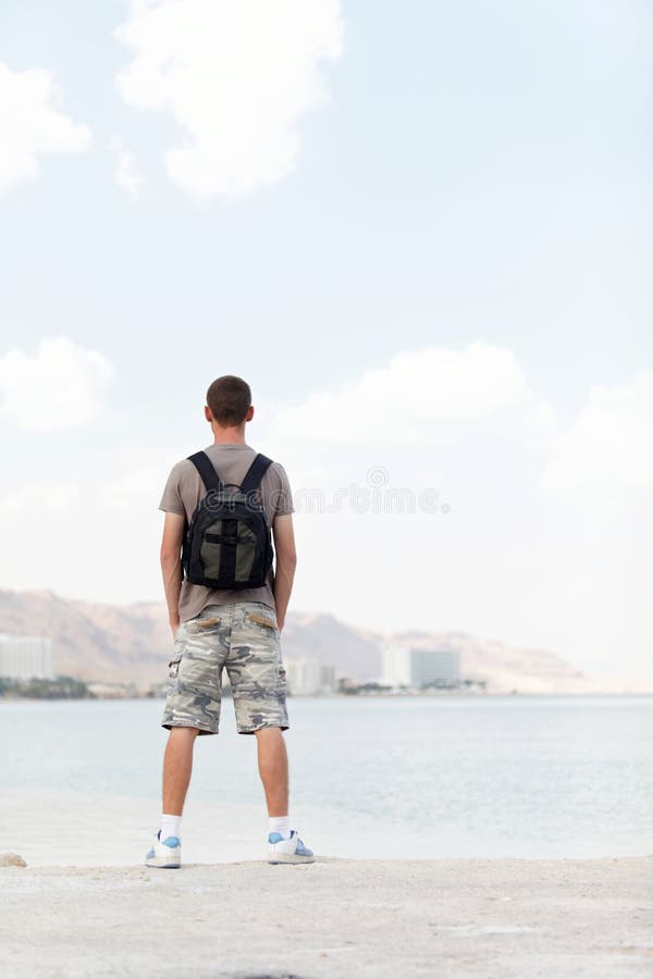 homme voyageur avec sac à dos debout sur une plage de sable au milieu des  rochers sur fond de mer 4888963 Photo de stock chez Vecteezy