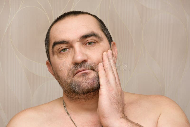 Un homme barbu de 40 ans touche des chaumes sur le visage avec la main. il est temps de se raser la barbe. concept de soins du vis images libres de droits