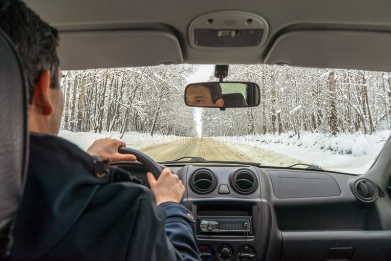 Un homme conduisant sur une route de campagne enneigée à travers la forêt enneigée pendant la journée nuageuse d'hiver Voyage en photo stock Un homme conduisant sur une route de campagne enneigée à travers la forêt enneigée pendant la journée nuageuse d'hiver Voyage en photo stock