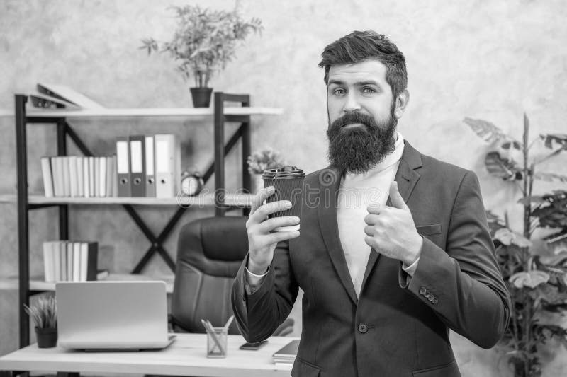 Un homme d'affaires barbu confuse boire du café à emporter dans le bureau montrer le pouce café pause image stock