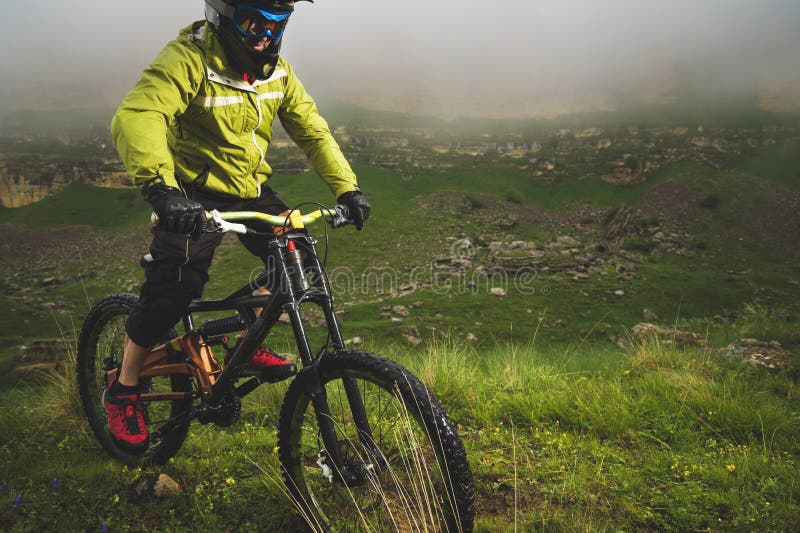 Un homme dans un casque de montagne montant un vélo de montagne monte autour de la belle nature par temps nuageux downhill image libre de droits Un homme dans un casque de montagne montant un vélo de montagne monte autour de la belle nature par temps nuageux downhill image libre de droits
